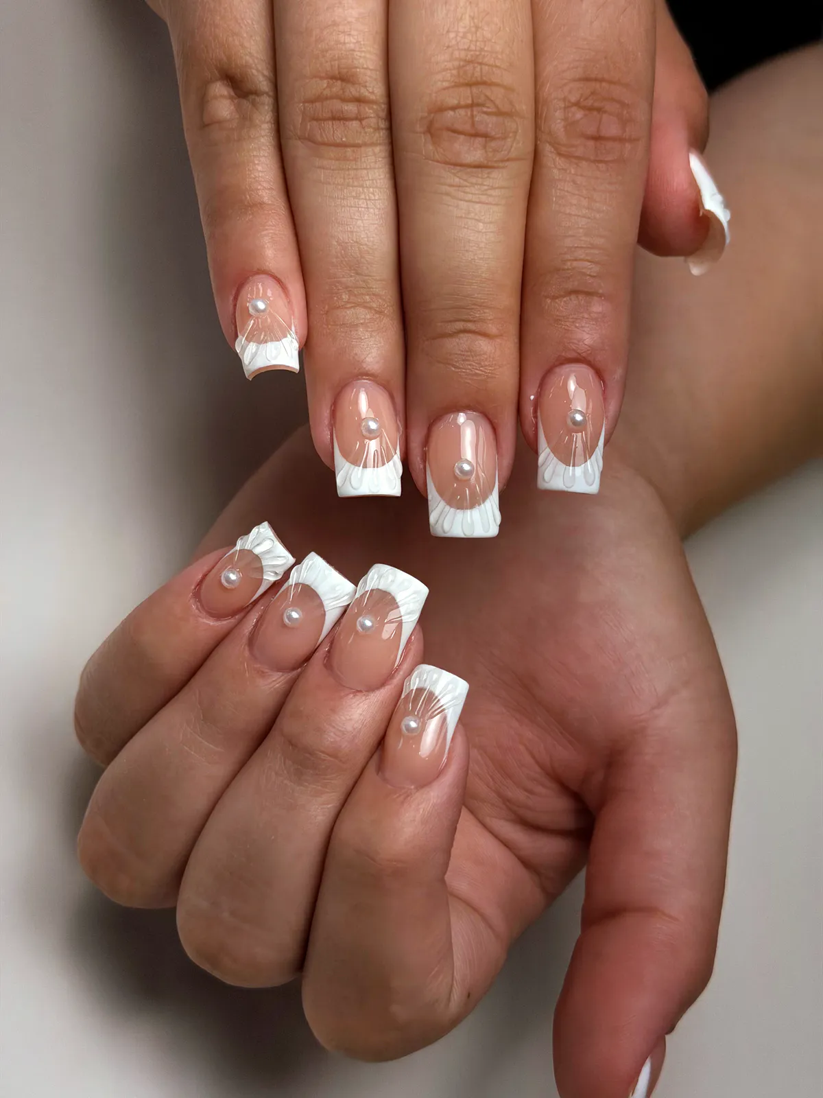 Nude square nails with white shell-ridge French tips and a pearl on each nail, by BeautyFusionClau in Sarasota, Florida